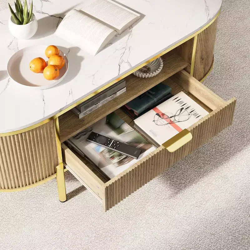 Tavolino da caffè scanalato moderno con cassetto, piano ovale in finto marmo da 122 cm e gambe dorate per soggiorno